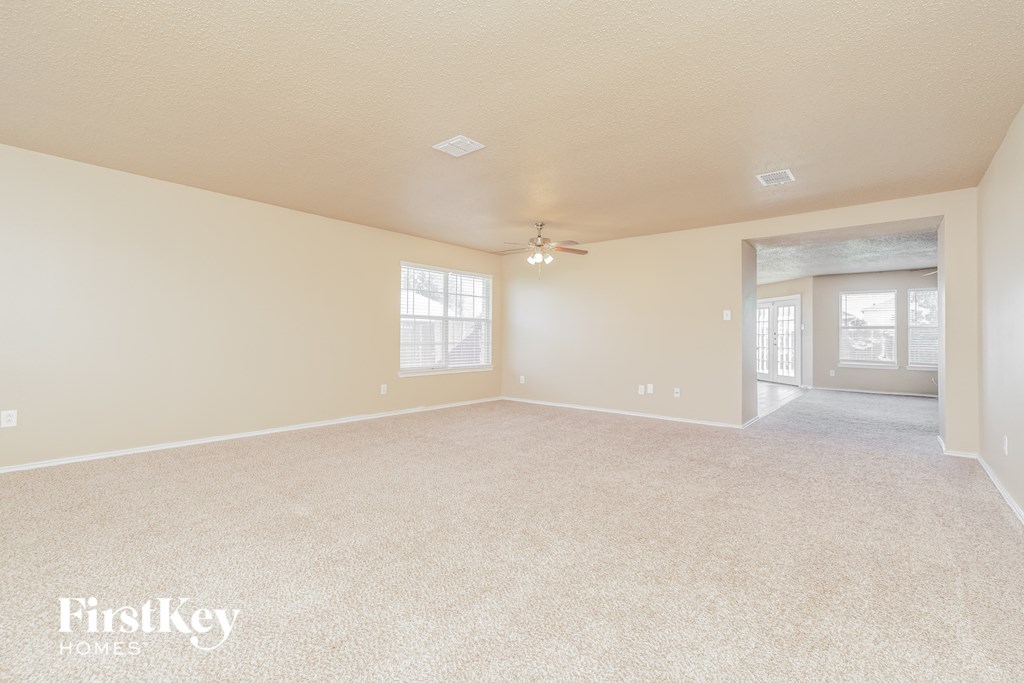 a spacious living room with carpeting and a ceiling fan