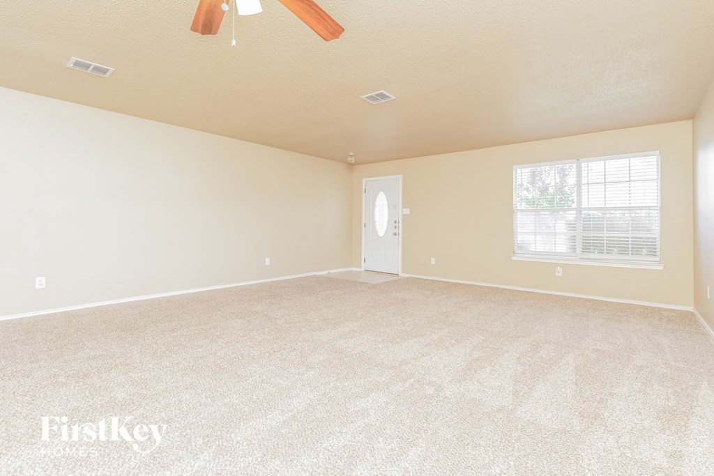 an empty living room with a ceiling fan and a window
