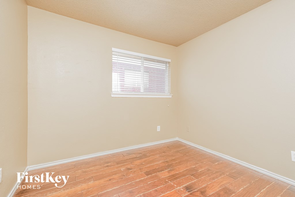 a bedroom with wood floors and a window