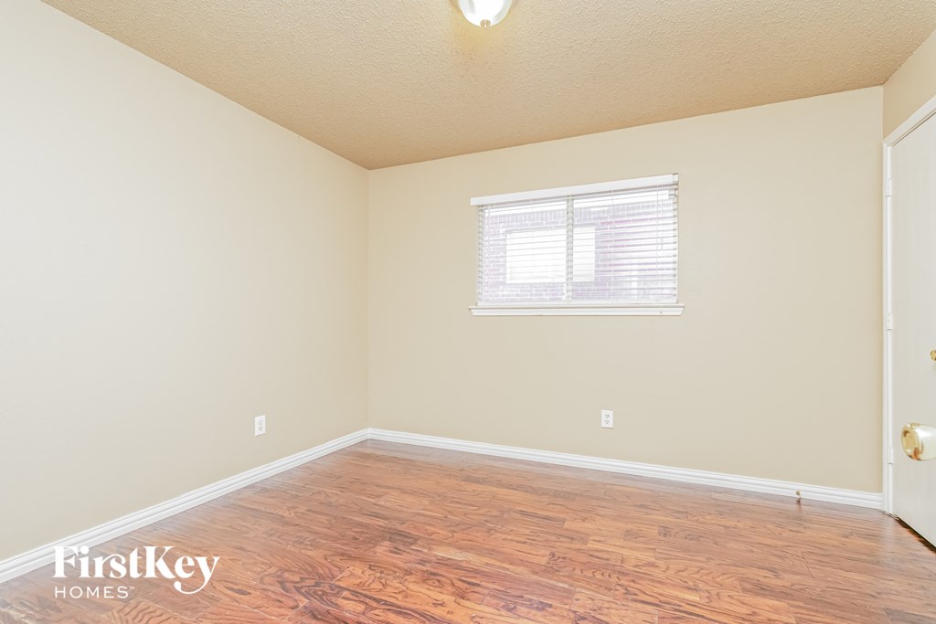 a bedroom with wood flooring and a window