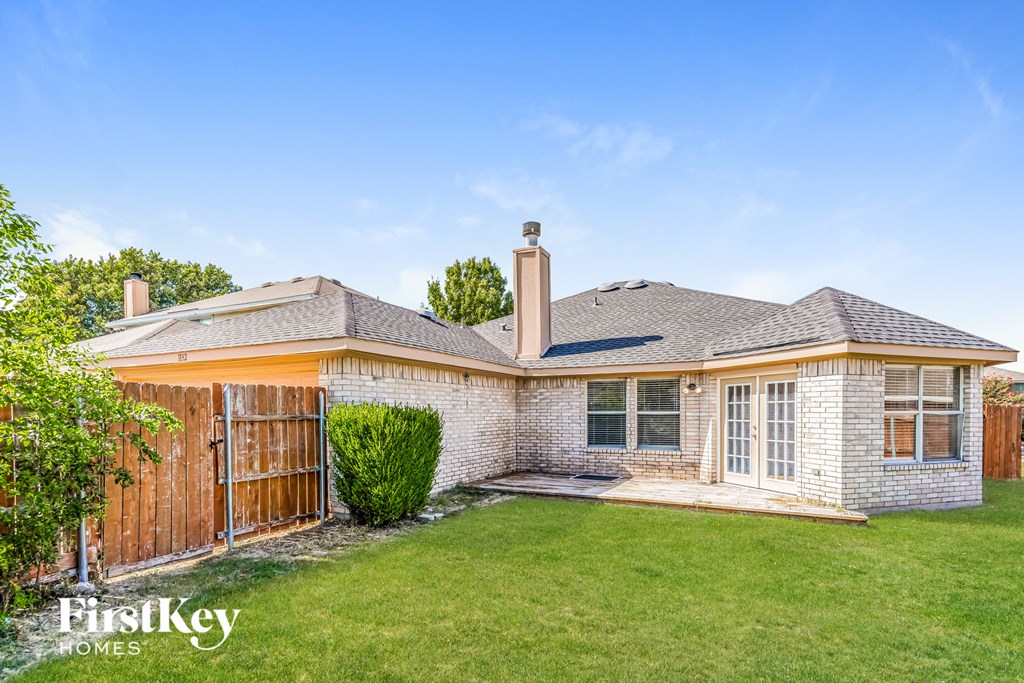 a small brick house with a yard and a wooden fence