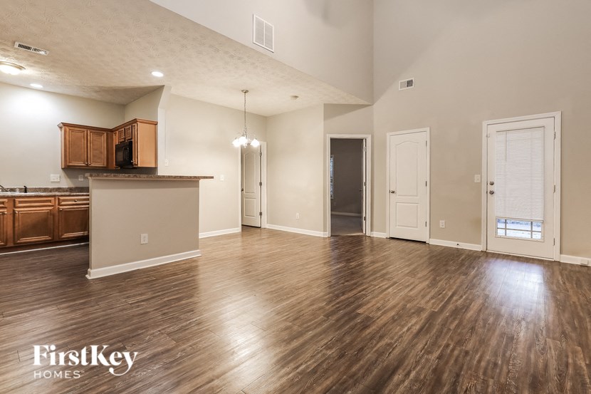 an empty living room and kitchen with wood flooring