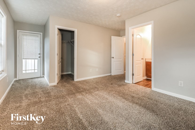 an empty living room with carpet and a door to a closet