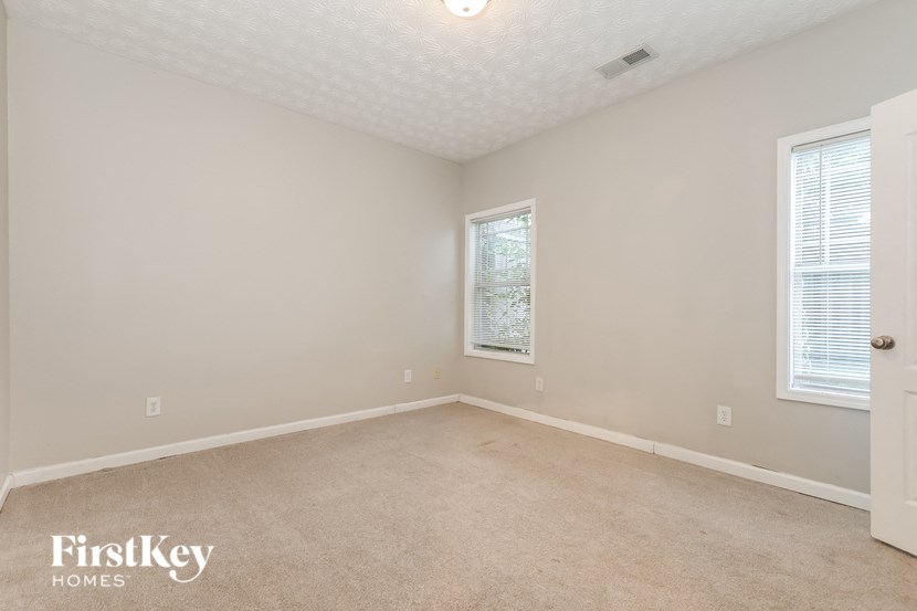 a bedroom with a carpeted floor and two windows