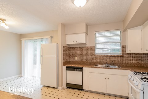 A kitchen with a white fridge, dishwasher and stove.