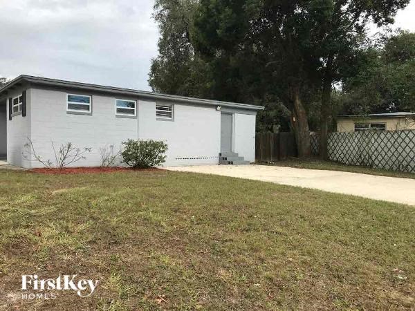 a small white house with a yard and a driveway