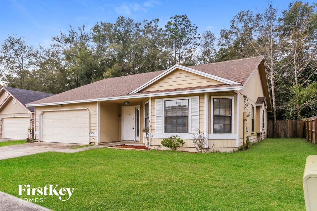 a small tan house with a yard and a driveway