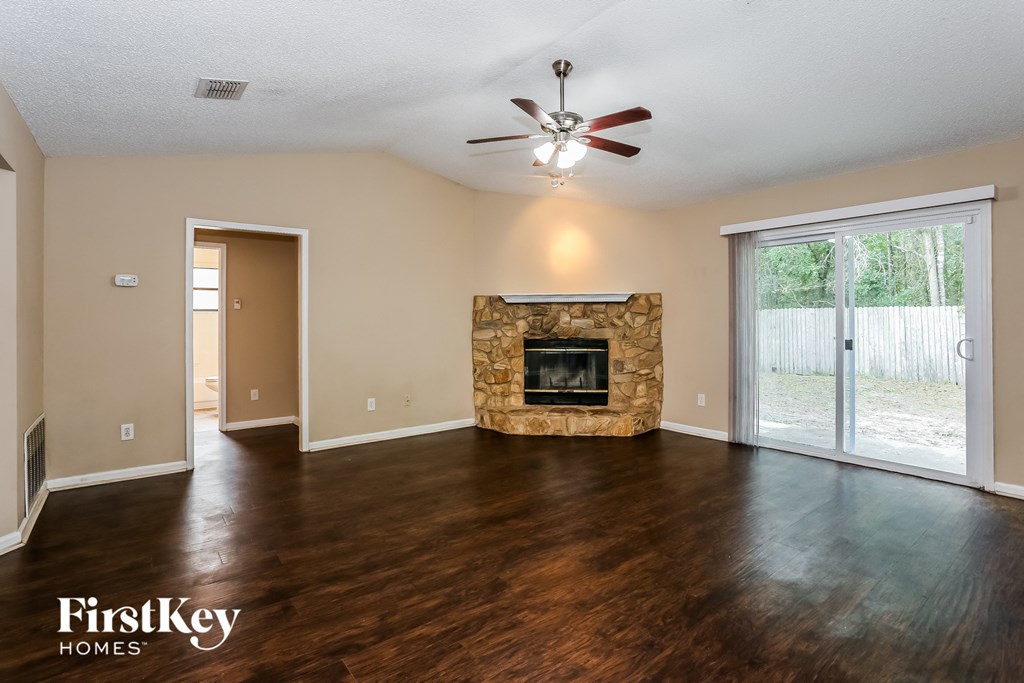 an empty living room with a fireplace and a ceiling fan