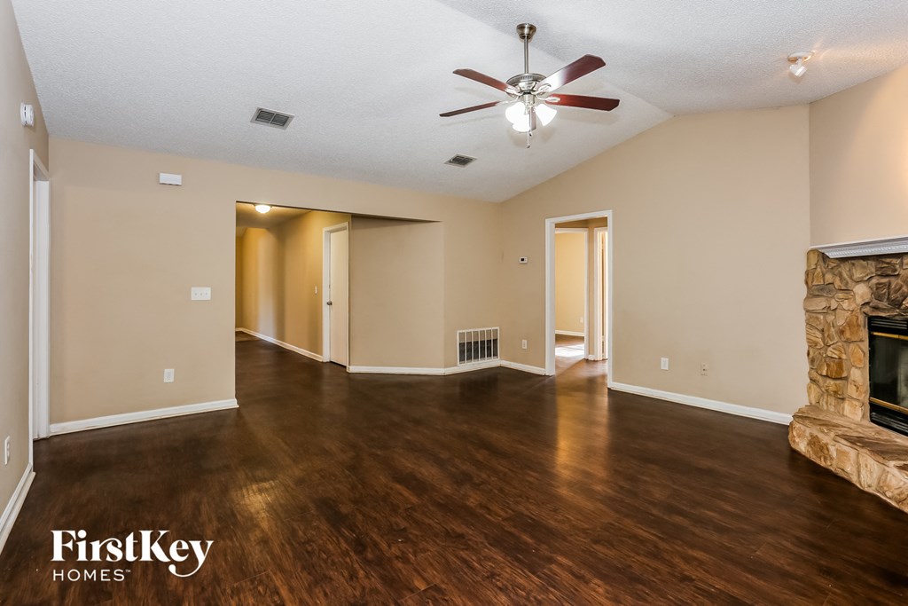 an empty living room with a fireplace and a ceiling fan