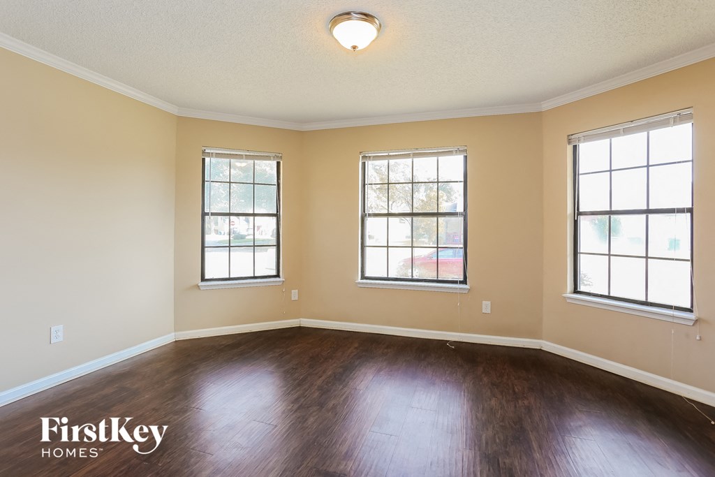 the living room of an empty house with wood floors and three windows