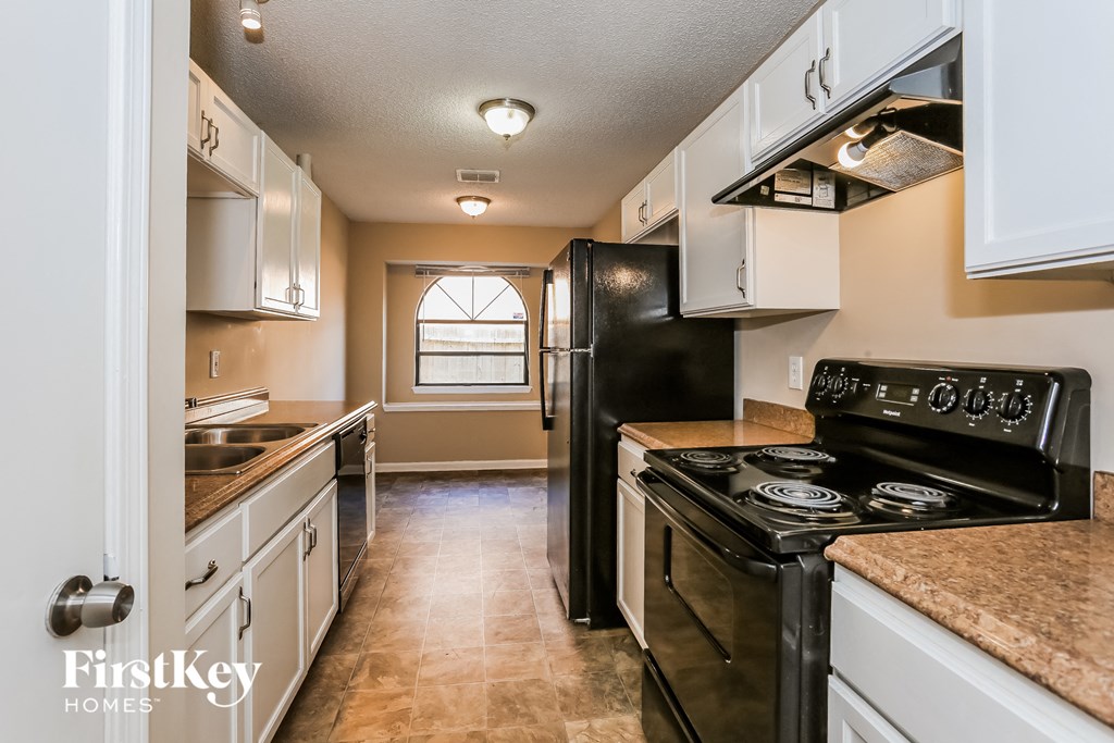 an empty kitchen with black appliances and white cabinets