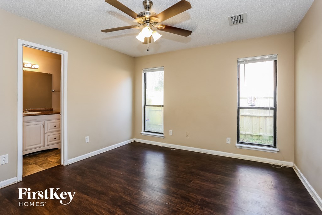 an empty living room with wood floors and a ceiling fan