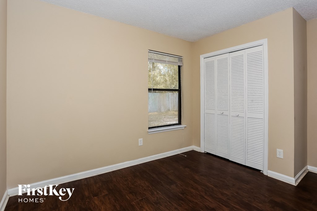 the living room of an empty house with wooden floors and a window and a closet