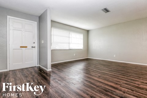 the living room of an empty house with wood floors and a white door