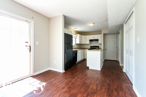 A kitchen with white cabinets and a black fridge.