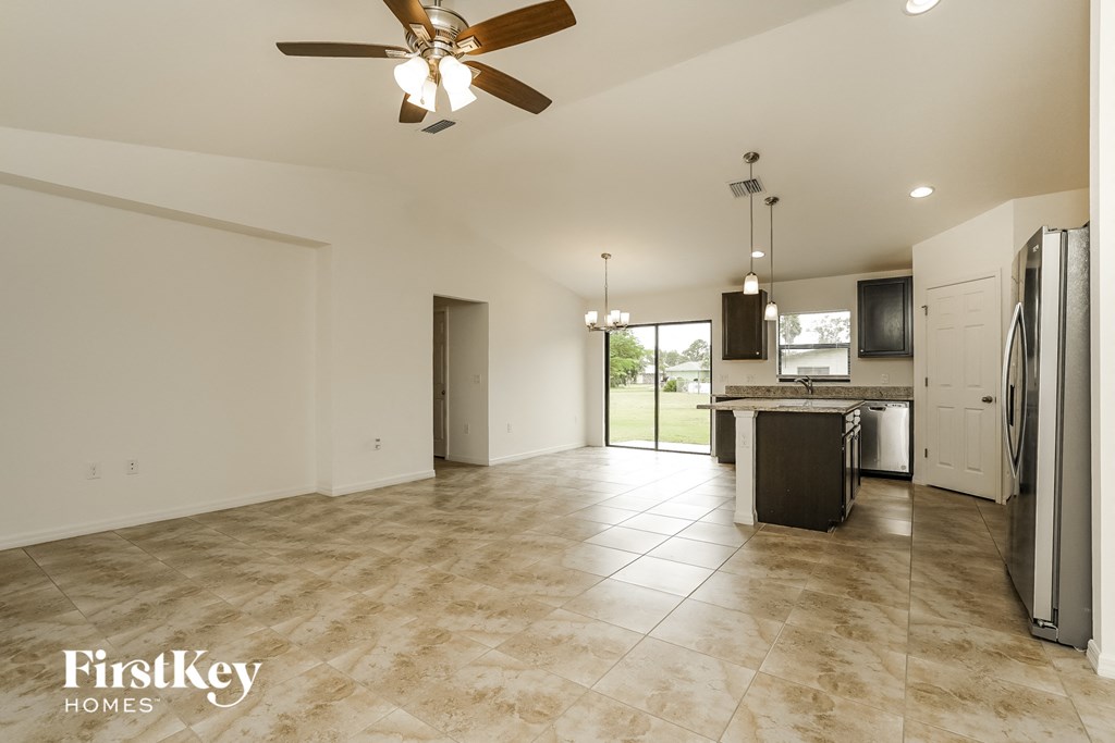 an open kitchen and living room with stainless steel appliances and tile flooring