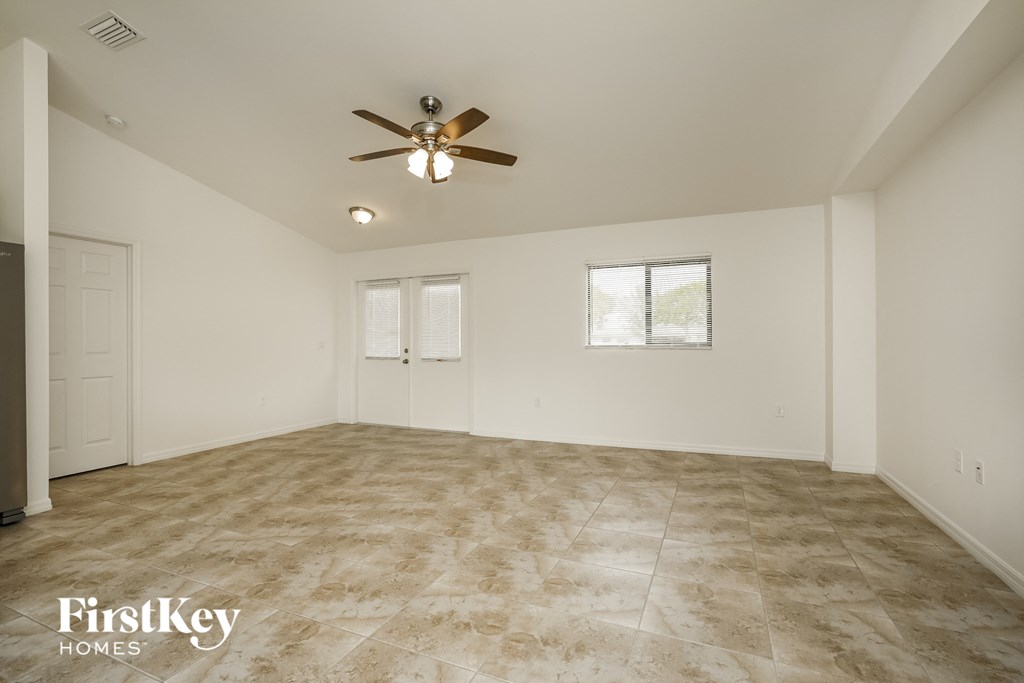the spacious living room with tile flooring and a ceiling fan