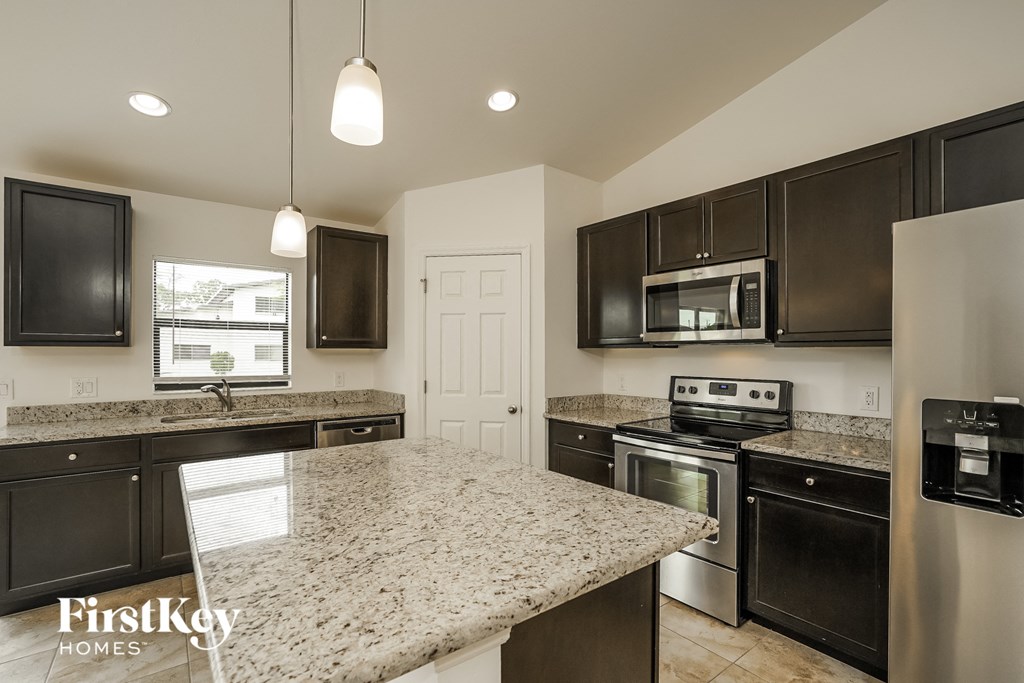 an updated kitchen with granite counter tops and black cabinets
