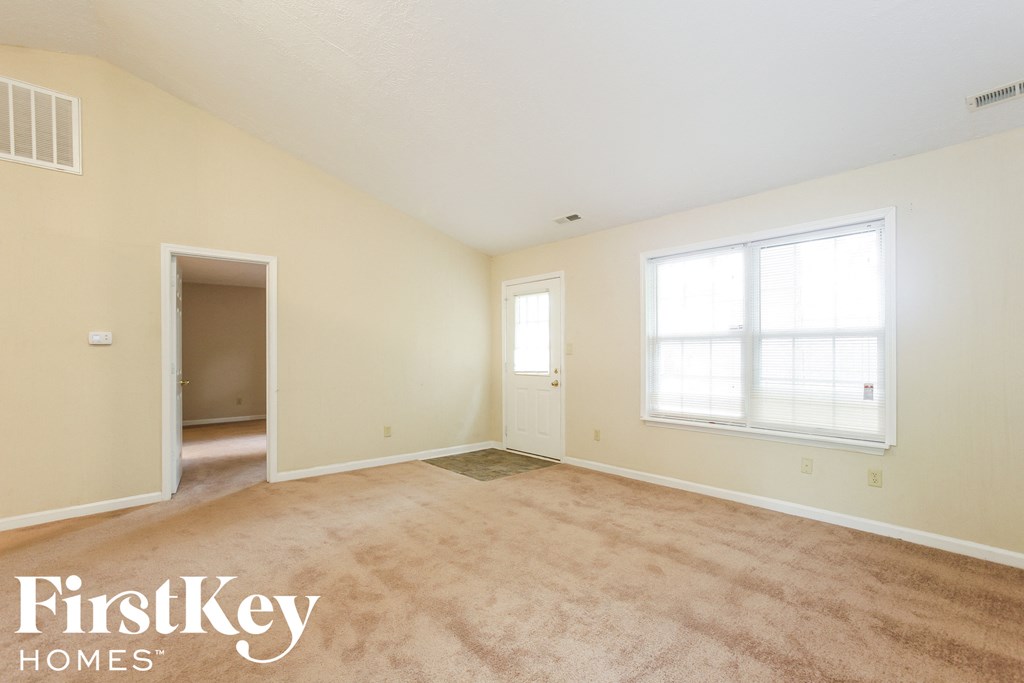 the living room of an empty house with carpet and a window