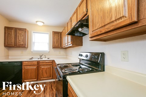 a kitchen with wood cabinets and black appliances and white countertops