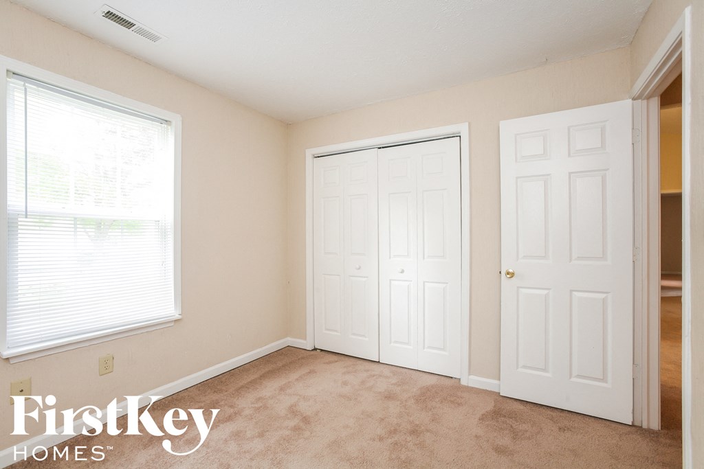 a bedroom with two closets and a window and a carpeted floor