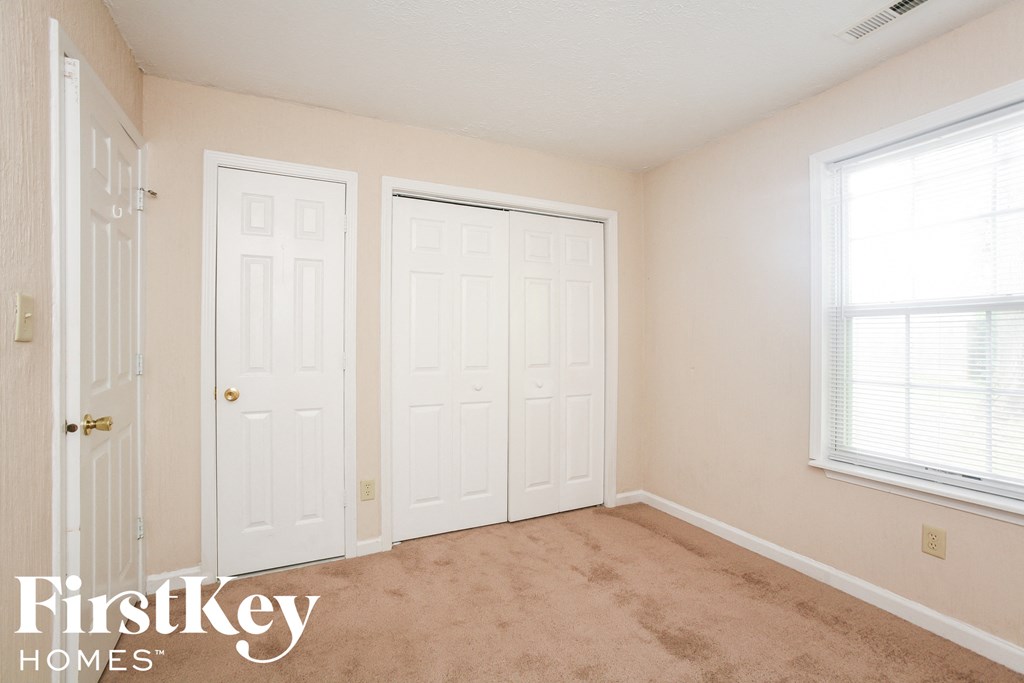 a bedroom with two closets and two doors and a carpeted floor