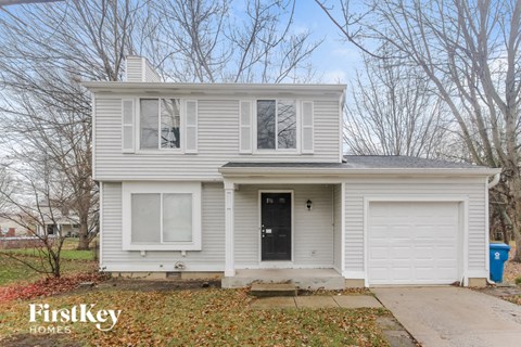 the front of a white house with a black door