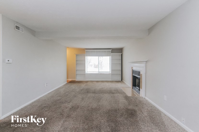 a spacious living room with carpet and a fireplace