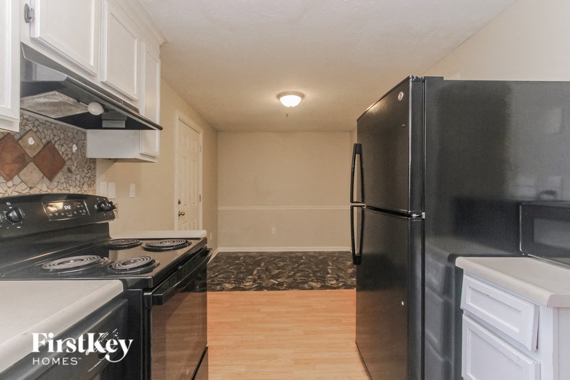 a kitchen with black appliances and white cabinets and a refrigerator