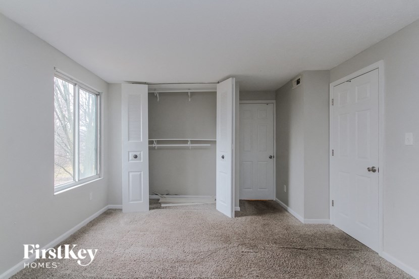 a bedroom with white closets and white doors and a carpeted floor