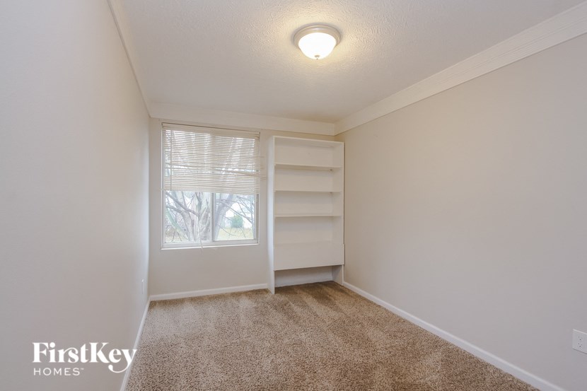 a bedroom with a large window and white shelves