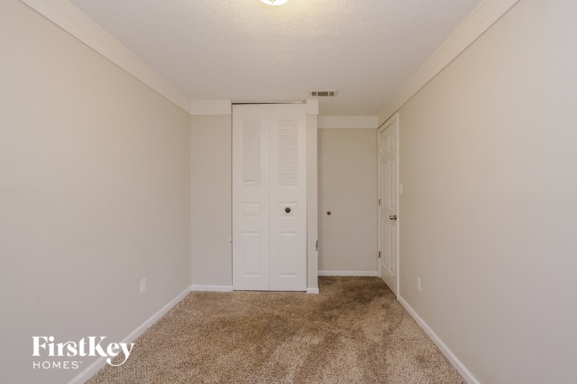 a bedroom with carpet and a door to a closet