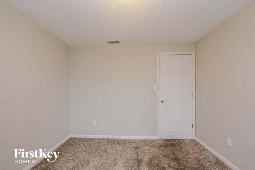 a bedroom with a white door and a carpeted floor
