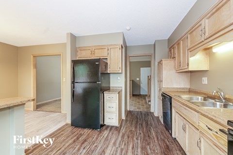 a kitchen with wooden floors and a black refrigerator