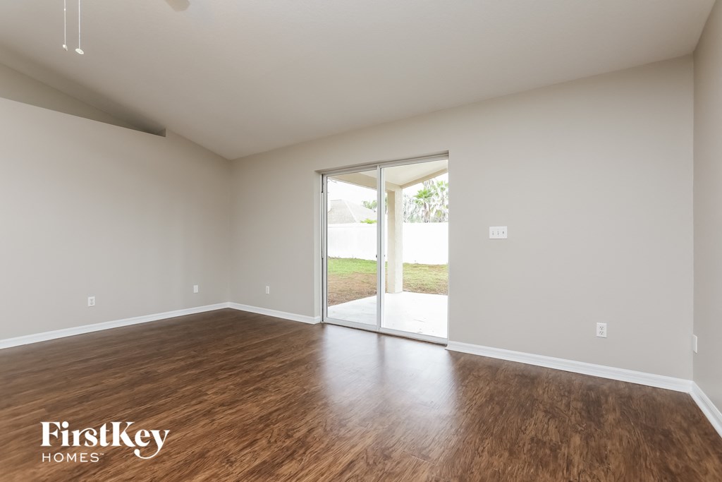 an empty living room with wood flooring and a sliding glass door