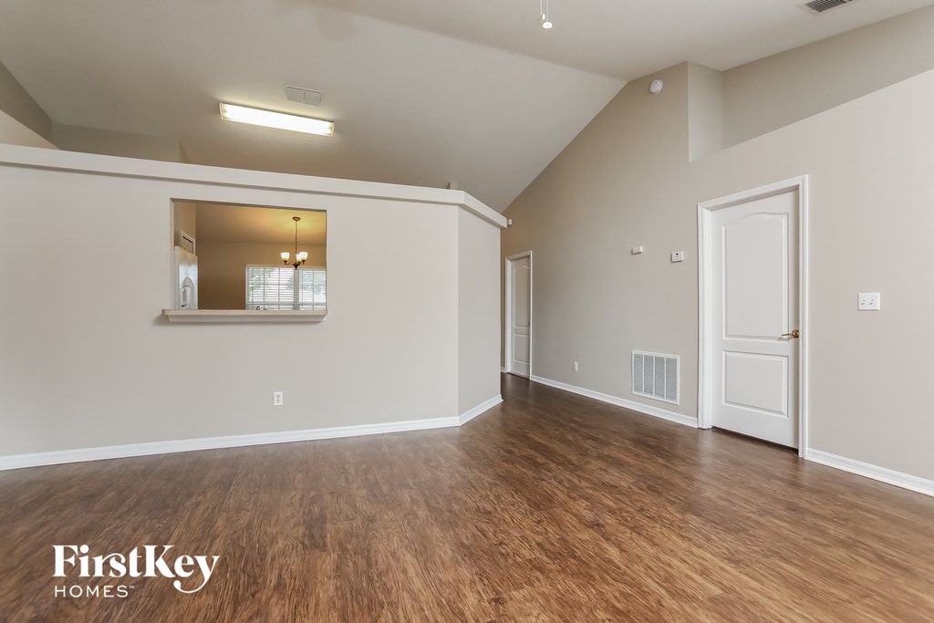 the spacious living room with hardwood flooring and white walls