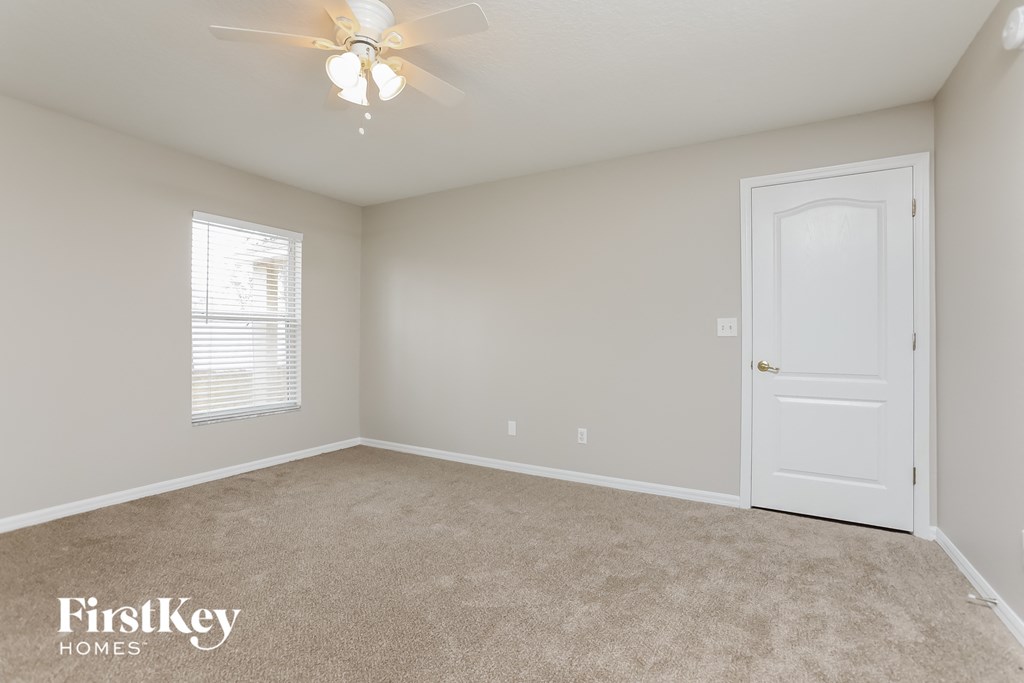 a bedroom with a white door and a ceiling fan