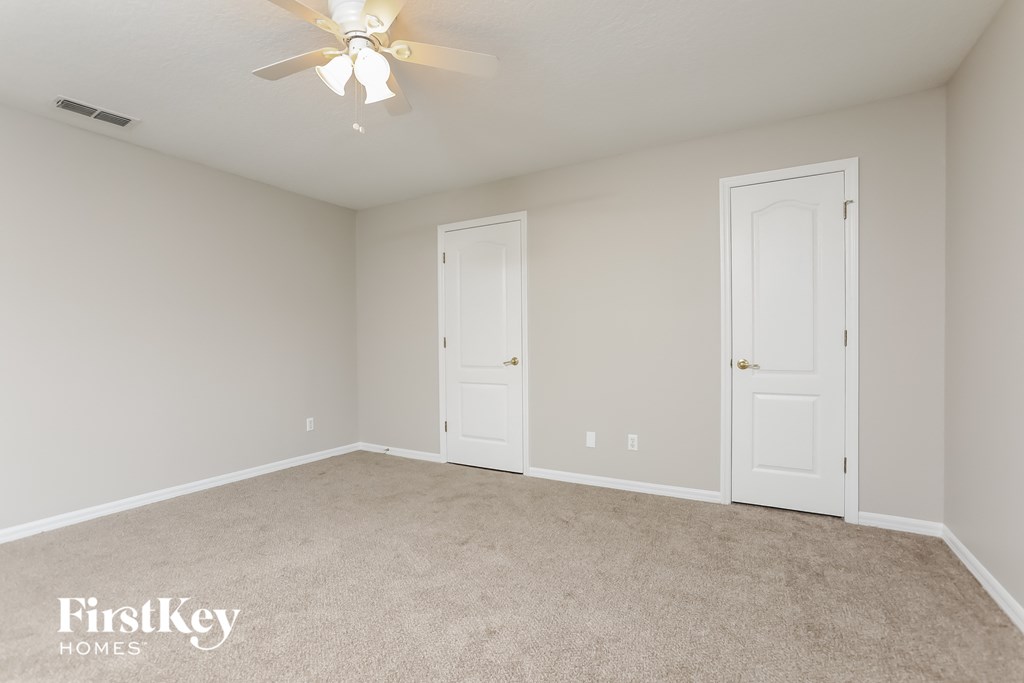 a bedroom with two doors and a ceiling fan