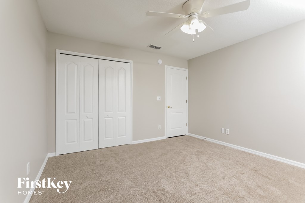 the living room of a new home with carpet and a ceiling fan