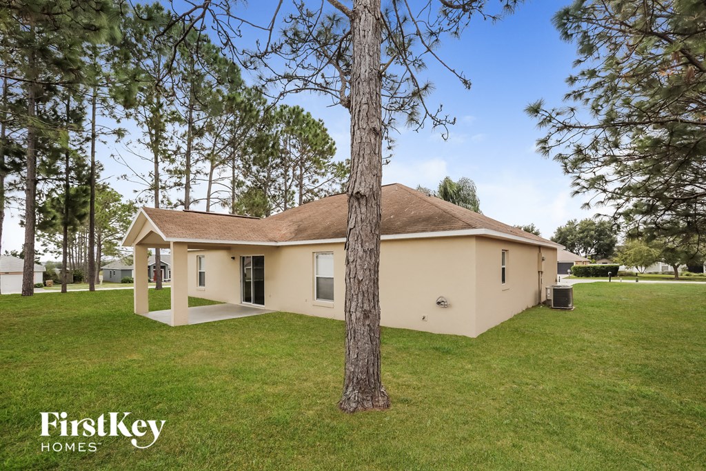 a yellow house with a tree in the grass