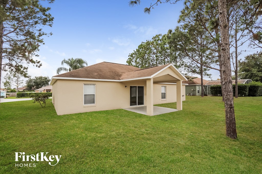 a small beige house in the grass with trees