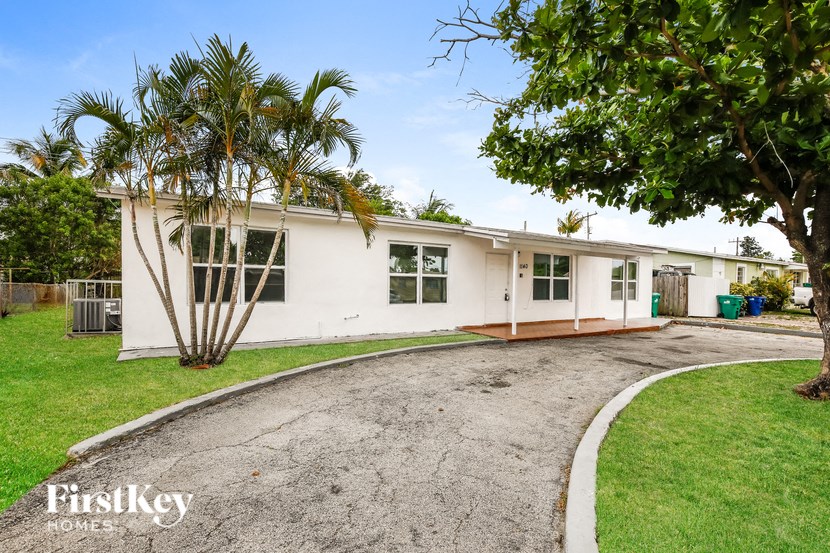 a white house with palm trees and a driveway