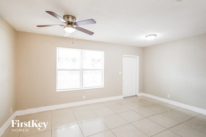 the spacious living room with ceiling fan and tiled floor