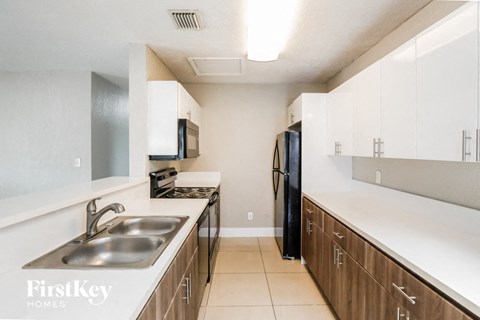 a kitchen with white counter tops and wooden cabinets and a sink