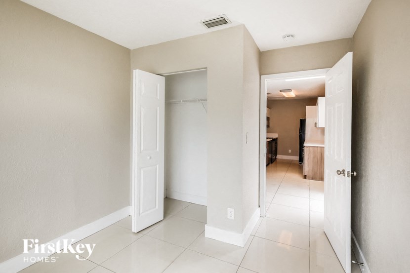 a hallway with a closet and a tiled floor and an open door to a