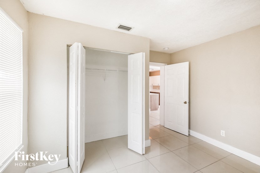 a walk in closet with an open door and a tiled floor in a room