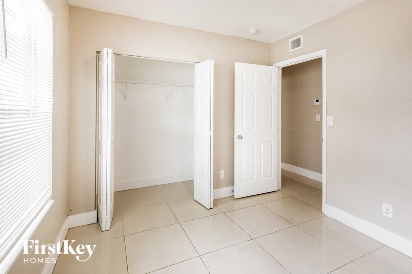 a bedroom with two closets and a tiled floor and two doors