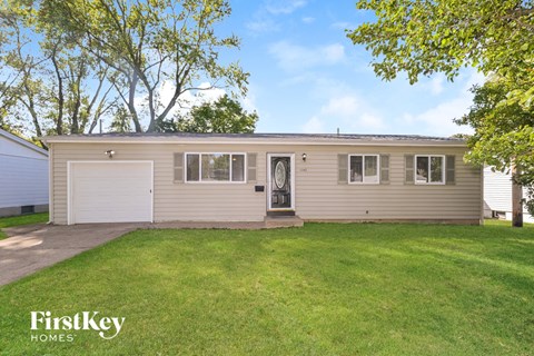 A small house with a garage door is surrounded by a grassy lawn.