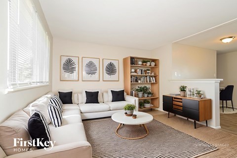 A living room with a white couch, a coffee table, and a bookshelf.