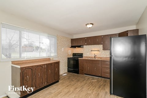A kitchen with wooden cabinets and a black refrigerator.